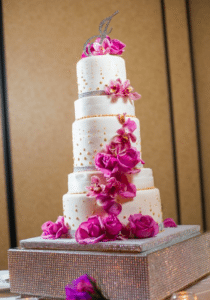 Hot pink flowers set of this towering wedding cake. Image provided by Hulse Photography